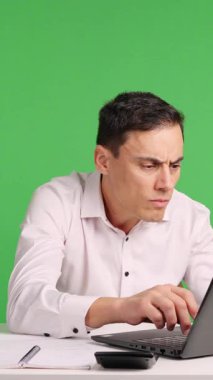 Çalışan, bir ofiste yeşil ekran karşısında dizüstü bilgisayarla çalışırken şok ve şaşkınlık yaşıyor.