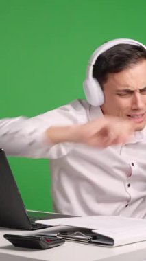 Kulaklık takan ofis çalışanı, masasında çalışırken yeşil ekran bir arka plana karşı patronunun varlığından habersiz müzik ve dans etmekten zevk alır.