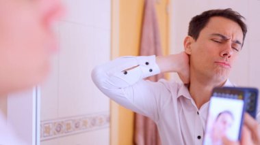 Office worker taking a selfie in a bathroom mirror while touching his neck, showing vanity and self absorption clipart