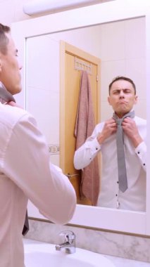 İyimser iş adamı banyodaki aynanın önünde kravatını düzeltiyor.