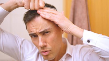 Seksi ve çok çekici bir adam banyoda saçını tarıyor.