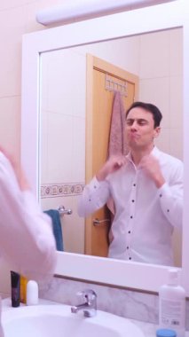 İş adamı aynada kendine bakıyor, giyiniyor ve önemli toplantıdan önce kendini motive ediyor.