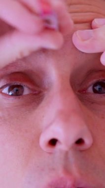 Kaşlarını ve burun kıllarını buduyor. Küçük bir elektrikli budayıcı kullanıyor. Günlük bakımını yapıyor.