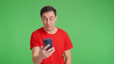 Video görüşmesi için akıllı telefonu kullanan, konuşan ve yeşil ekranda el kol hareketi yapan mutlu adam.