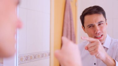 Banyodaki aynaya bakan bir iş adamı önemli bir toplantıdan önce motivasyon konuşması yapıyor.