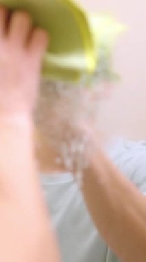 Temizlikçi kirli banyo aynasını sprey ve bezle temizliyor.