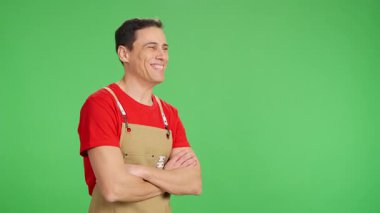 Kendine güveni tam bir girişimci kolları çapraz gülümseyen, önlük takan, krom bir arka plana karşı.