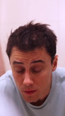 Adam uyandıktan sonra banyo lavabosunda yüzünü yıkıyor.