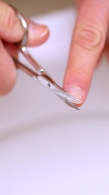 Klozetin üzerindeki tırnakları kesmek için tırnak makası kullanarak ellerini kapat.