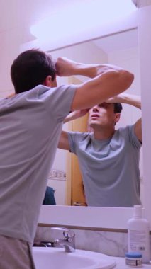 Sabah rutini, banyo aynasının önünde kaşlarını ve burun kıllarını kesen bir adam.