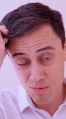 Endişeli adam randevusundan önce saçını tarıyor ve bakışlarını kontrol ediyor.