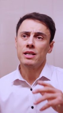 Aynada konuşma pratiği yapan iş adamı, gerginlik ve endişe gösteriyor.