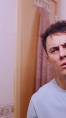 Genç adam uyandıktan sonra banyo aynasında yansımasına bakıyor.