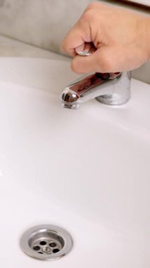 Bir el musluğu açtıktan sonra beyaz seramik lavaboda akan su.