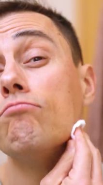 Banyoda yüzünü pamukla temizleyen bir adam.