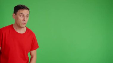 Yetişkin adam, yeşil ekranda izole edilmiş kopyalama alanını işaret eden tiksinti ve hoşnutsuzluk gösteren farklı yüzler yapıyor.