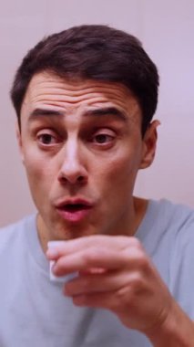 Adam sabah rutini sırasında banyo aynasının önünde gargara yapıyor.