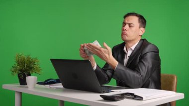 İş adamı yeşil ekranda farklı yüz ifadeleriyle para sayıyor.
