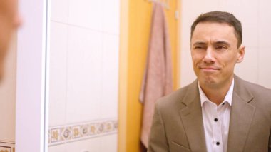 İş adamı aynada kendine hayran, kendinden emin ve işe başlamaya hazır hissediyor.