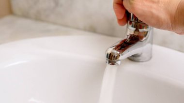 Banyonun musluğunu açıp lavaboya su dökerek suyu korumayı temsil ediyor.