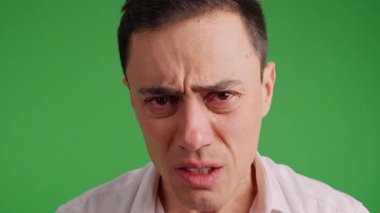 Gözyaşlarını tutmaya çalışan üzgün bir adamın portresi, yeşil bir ekranda izole edilmiş.