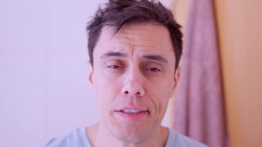 Yorgun adam, iş gününün başlamasından korkarak, yüzünü banyoda isteksizce yıkar.