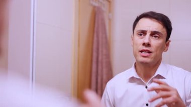 Aynada konuşma pratiği yapan iş adamı, gerginlik ve endişe gösteriyor.