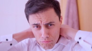 Kibirli adam saçını tarıyor ve aynada kendine surat yapıyor.