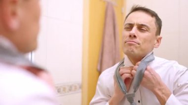 İyimser iş adamı aynaya bakıyor, kravatını düzeltiyor ve işe hazırlanıyor.