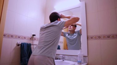 Sabah rutini, banyo aynasının önünde kaşlarını ve burun kıllarını kesen bir adam.