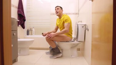Tuvalette otururken tuvalet kağıdı rulosunu bitirdiğini fark eden adam.