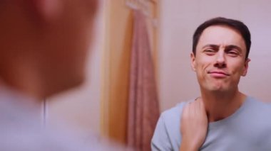 Narsist adam yüzünü buruşturuyor ve banyo aynasında kendine hayran.