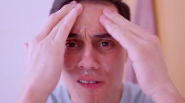 Adam yüzüne krem sürüyor, dudaklarına kakao sürüyor.