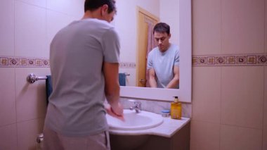 Adam ev içi tuvalette el yıkama ve kurutma rutini uyguluyor.