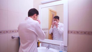 İş adamı aynaya bakıyor, burnunu siliyor ve mendilin içeriğinden korkuyor.