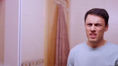 Endişeli adam banyodaki aynada saçını tarıyor, randevudan önce kendini güvensiz hissediyor.