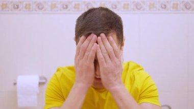 Banyoda şiddetli karın ağrısı çeken bir adam.