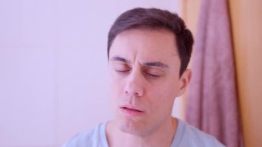 Kötü soğuk algınlığı geçiren ve burnunu mendille silen bir adam.