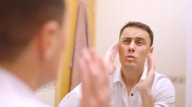 İşadamı banyoda aynanın önünde saçını tarayıp kontrol ediyor.