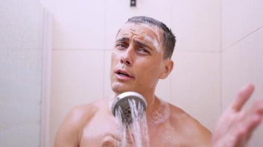 Duşun tadını çıkaran bir adamın mikrofon gibi duş başlığıyla şarkı söylemesi.