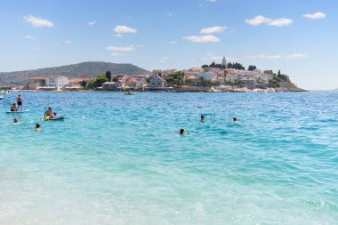 Turistler, Primosten eski kenti yakınlarında berrak su ve yaz tatili faaliyetlerinin keyfini çıkarıyorlar