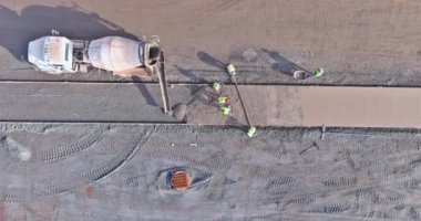 İşçiler kaldırım inşaatı sırasında beton kamyonu çimento döküyor