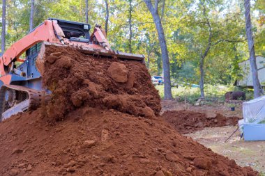 İnşaat alanında peyzaj projesi için toprak taşımak için kullanılan küçük bir traktör.