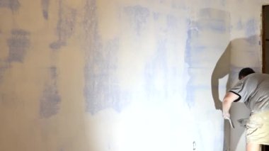 İnşaat alanında çalışan bir işçi macunu spatulayla bitirmeden önce alçıpan üzerine mala ile macun sürer..