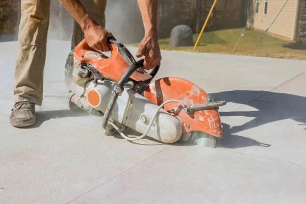 Using diamond bladed saw machine, construction worker cuts concrete sidewalks