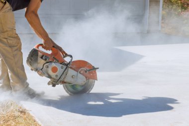 İnşaat işçisi, çalışan elmas bıçaklı kesikler beton kaldırım testeresi ile kesilmiş.