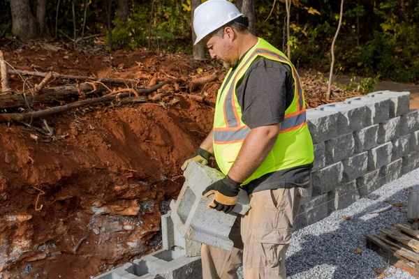 stock image Construction site contractor works on establishing large block retaining wall that has as construction process