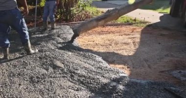 İnşaat alanındaki bir çalışan, yeni evin yakınındaki garaj yoluna ıslak beton döküyor..