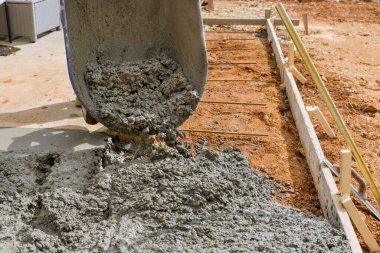 İnşaat müteahhitleri beton inşaat projesinde çalışırken garaj yolunu dökerken ıslak beton döküyorlar.