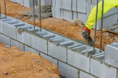Tuğlacılar beton bloklar kullanarak bina inşa etmek için duvara beton bloklar döşüyorlar.